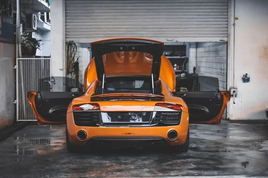 An orange sports car with open doors in a garage, showcasing its luxury design.
